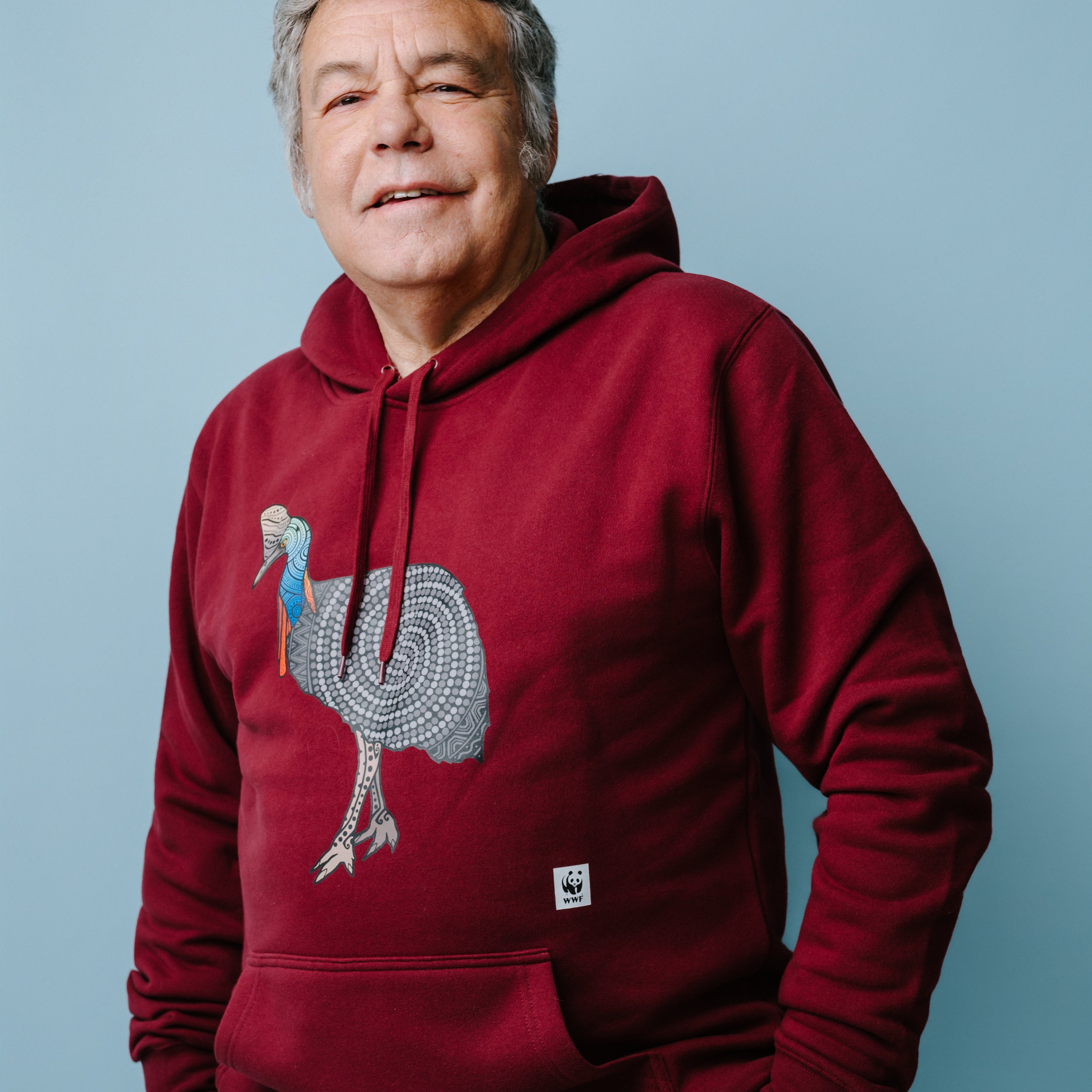 Man wearing a dark red hoodie with a cassowary graphic design on a blue background. WWF-Australia product.
