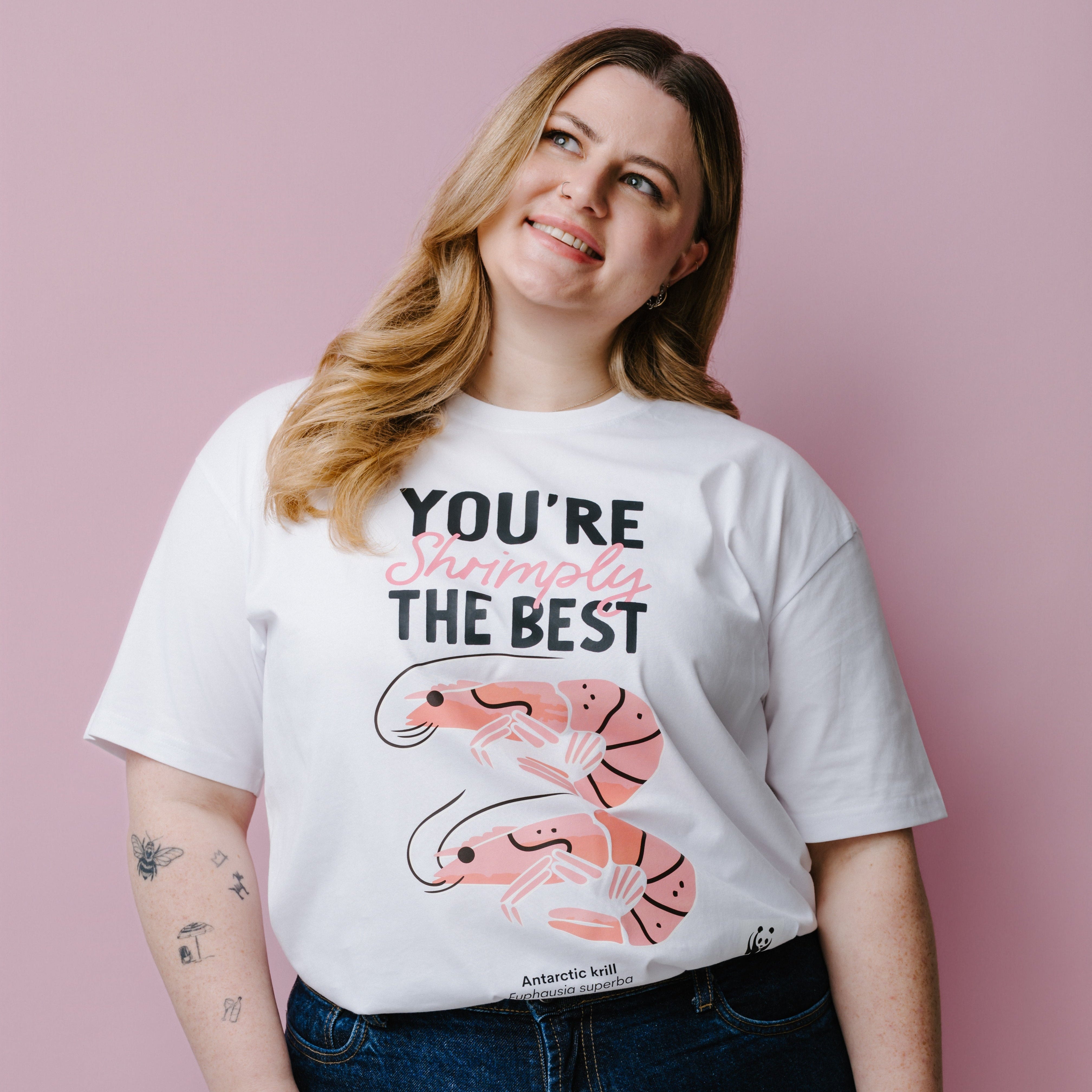 Person wearing a white t-shirt with shrimp graphics and text, "You're Shrimply The Best" against a pink background. Product is a WWF-Australia T-Shirt.