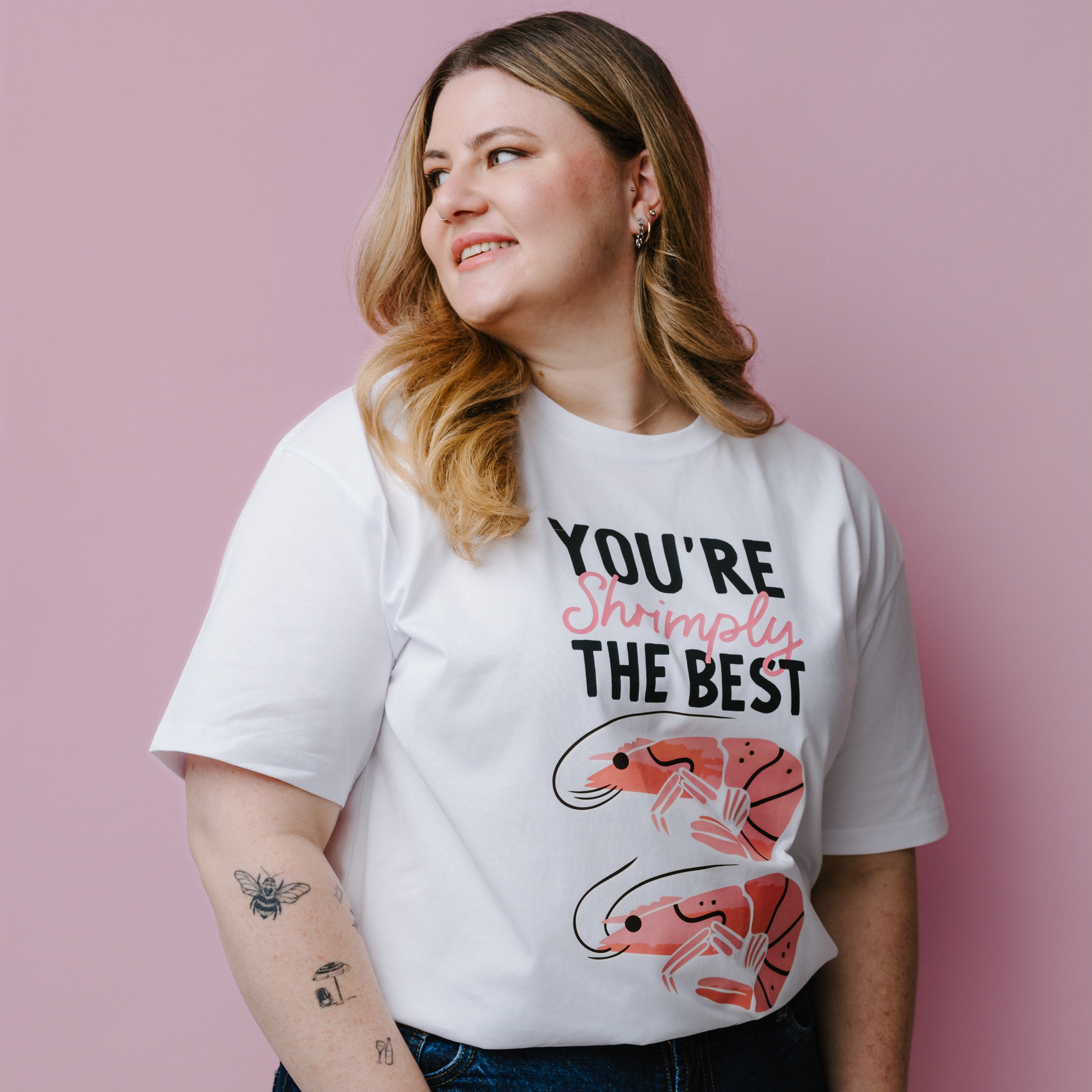 Person wearing a white t-shirt with shrimp graphics and text, "You're Shrimply The Best" against a pink background. Product is a WWF-Australia T-Shirt.