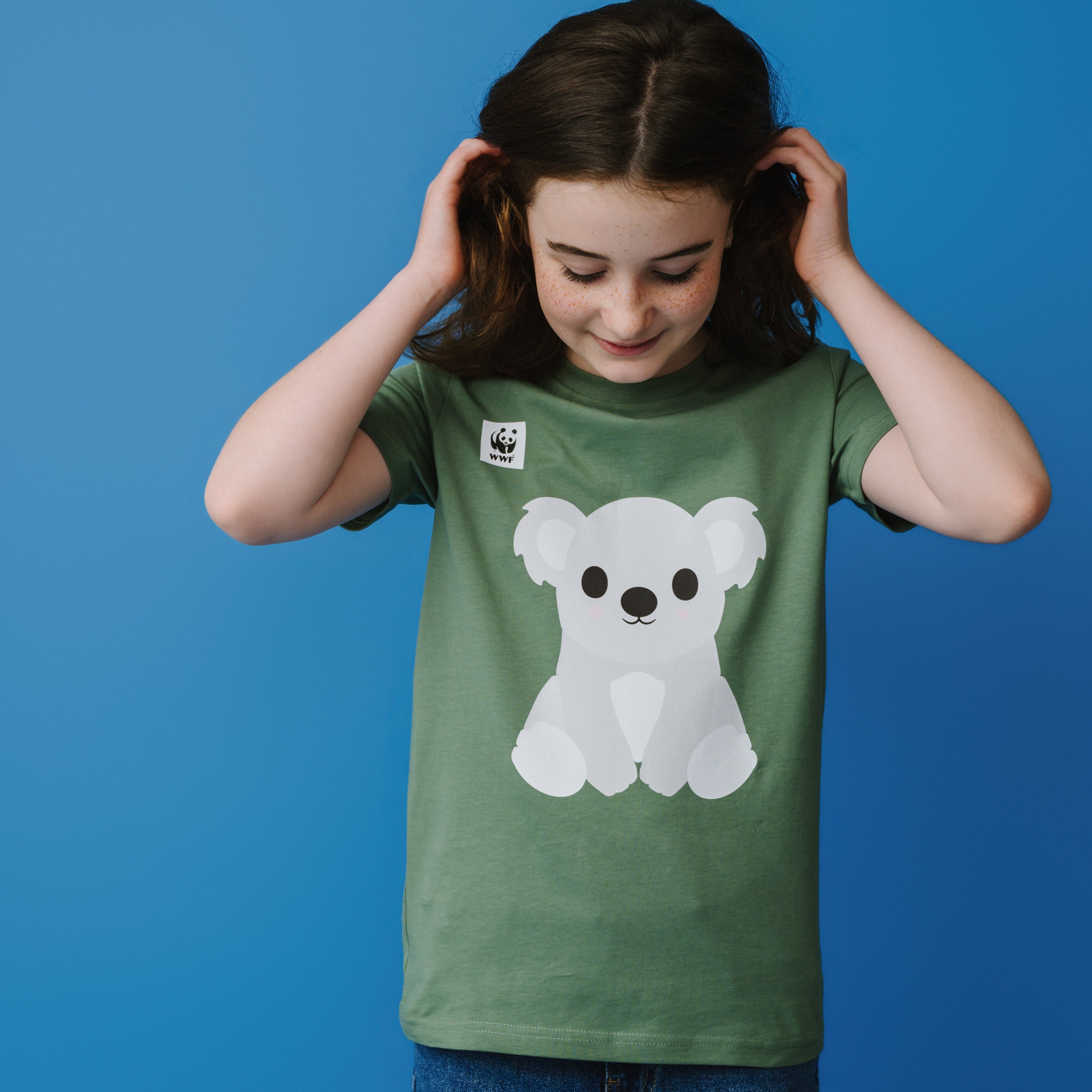 Child wearing a green t-shirt with a koala graphic on a blue background