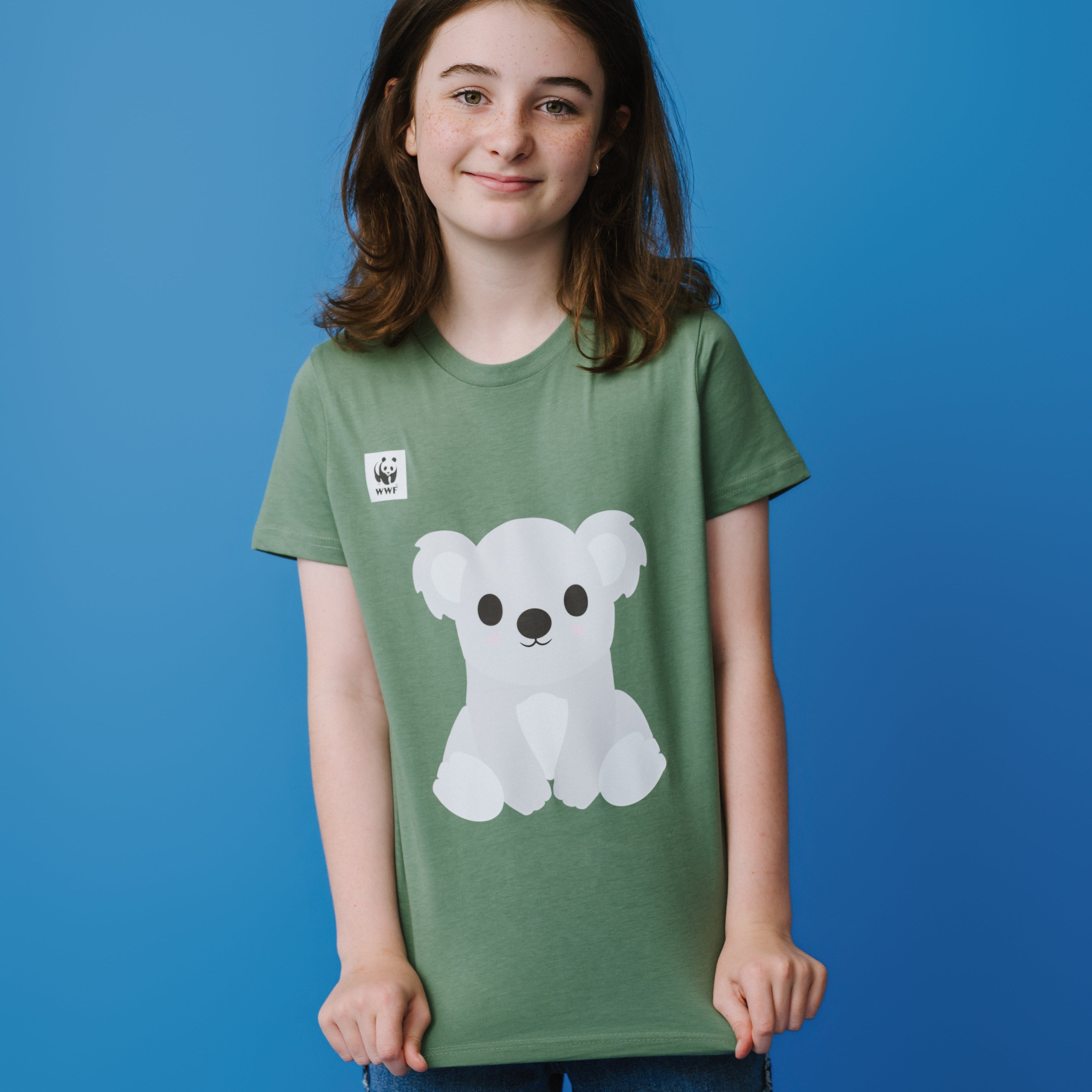 Girl wearing a green t-shirt with a light grey and white koala design on a blue background