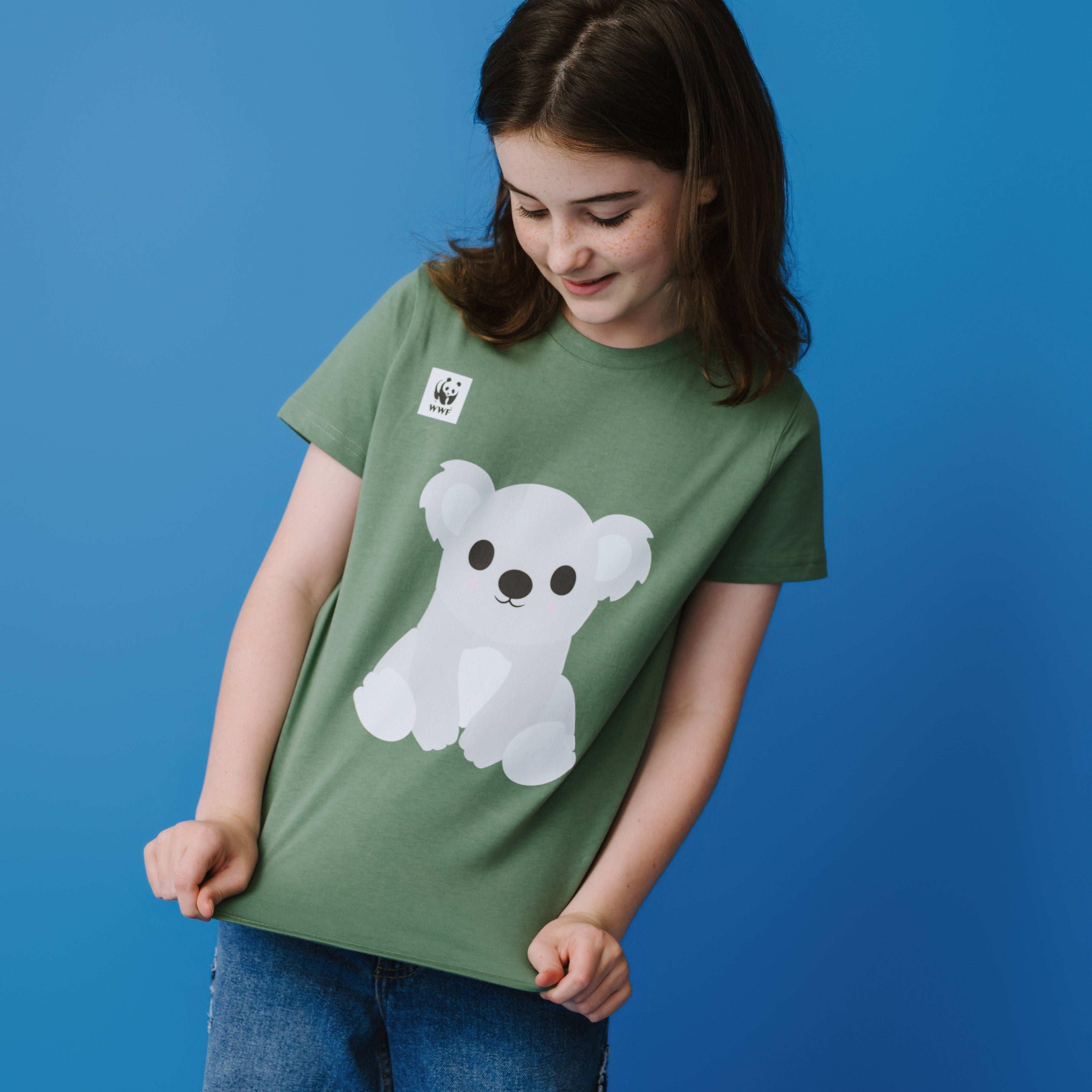 Child wearing a green t-shirt with a white and grey koala graphic on a blue background