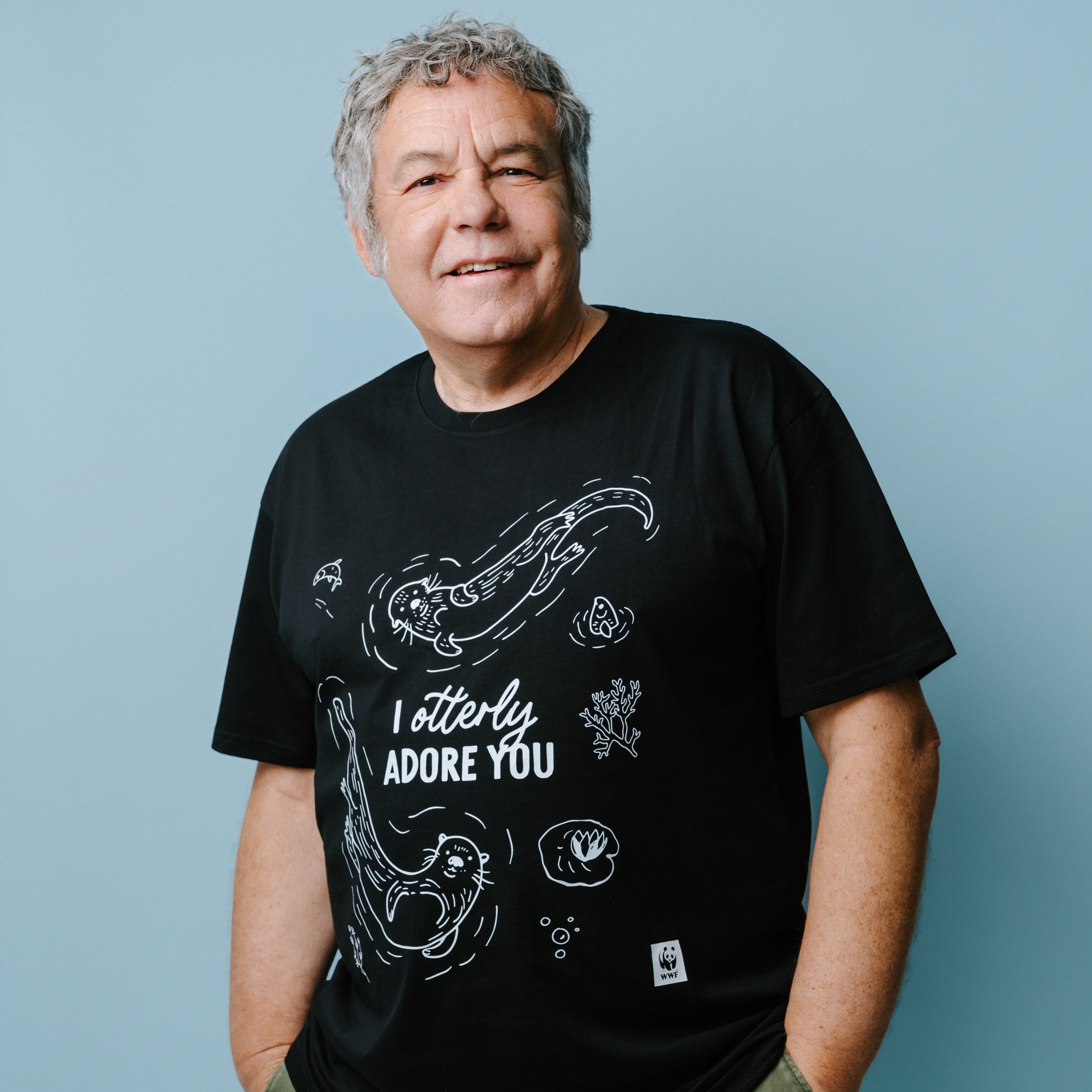 Man wearing a black t-shirt with white graphics featuring illustrations of 2 otters and text, "I otterly adore you" against a blue background. WWF-Australia product.