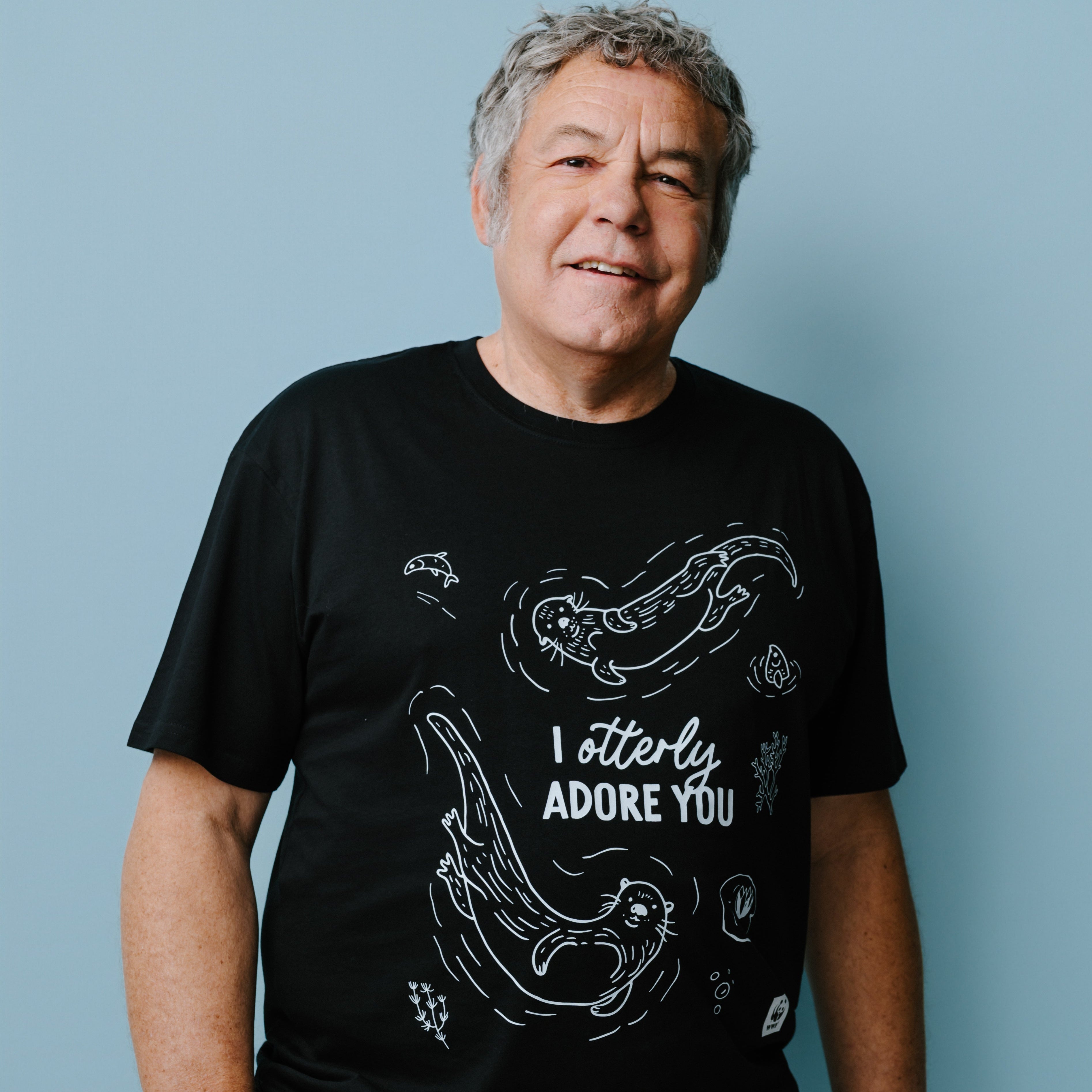 Man wearing a black t-shirt with white graphics featuring illustrations of 2 otters and text, "I otterly adore you" against a blue background. WWF-Australia product.
