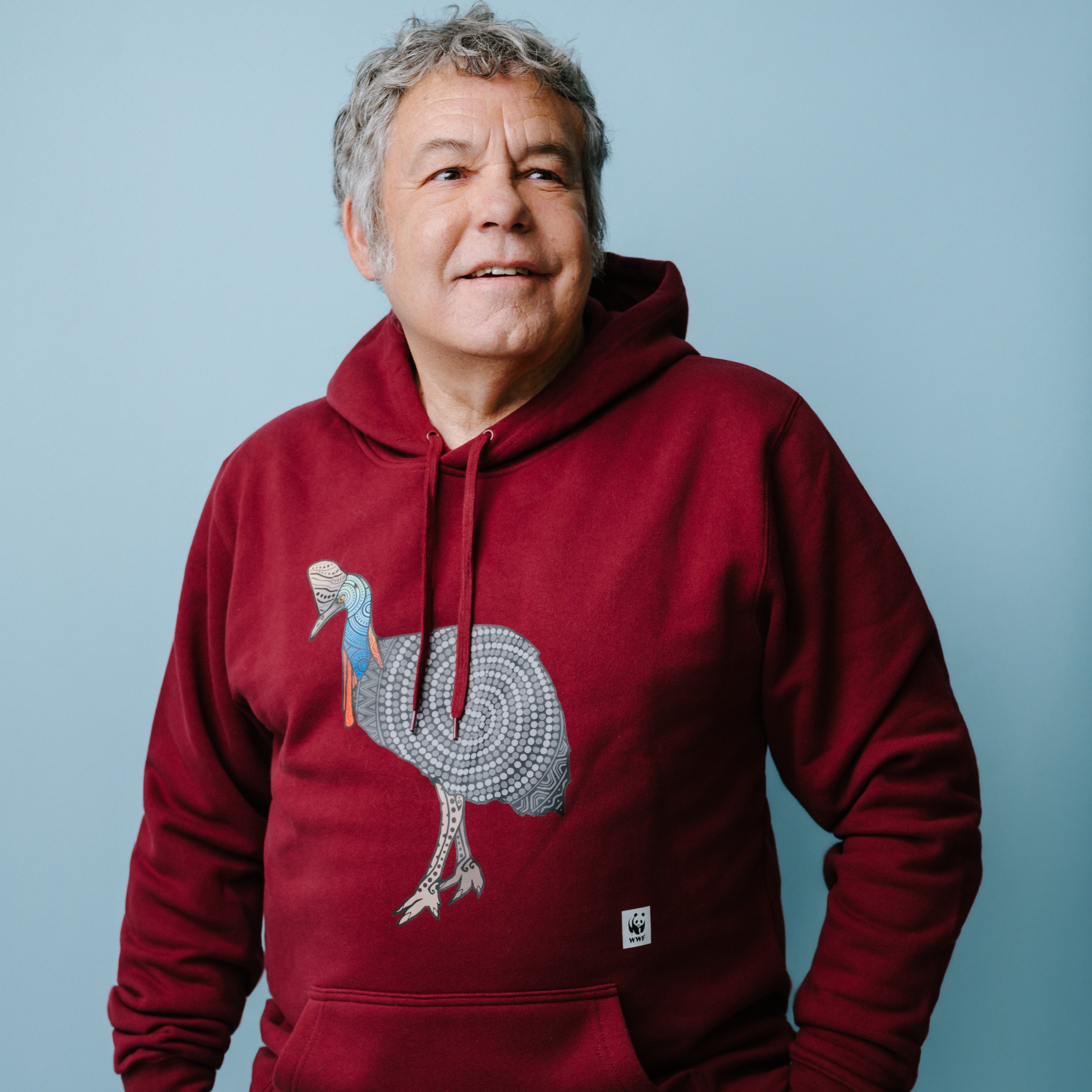 Man wearing a dark red hoodie with a cassowary graphic design on a blue background. WWF-Australia product.