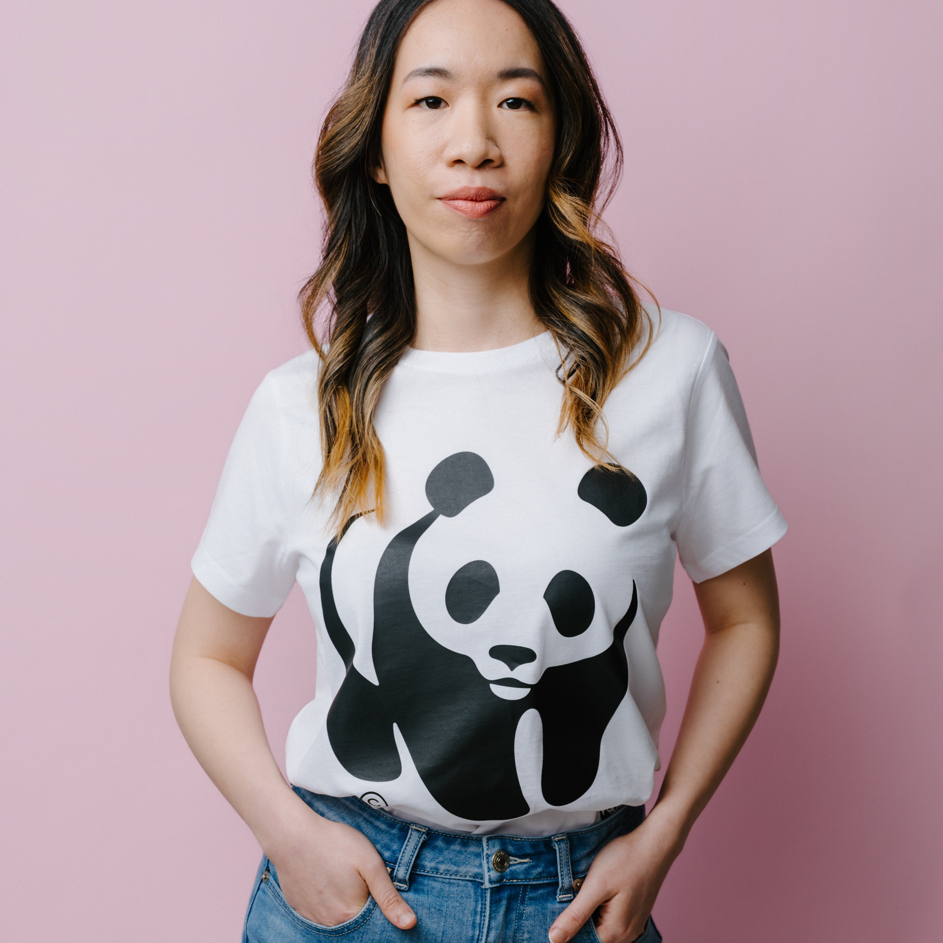 A woman wearing a white WWF Panda logo t-shirt against a pink background.