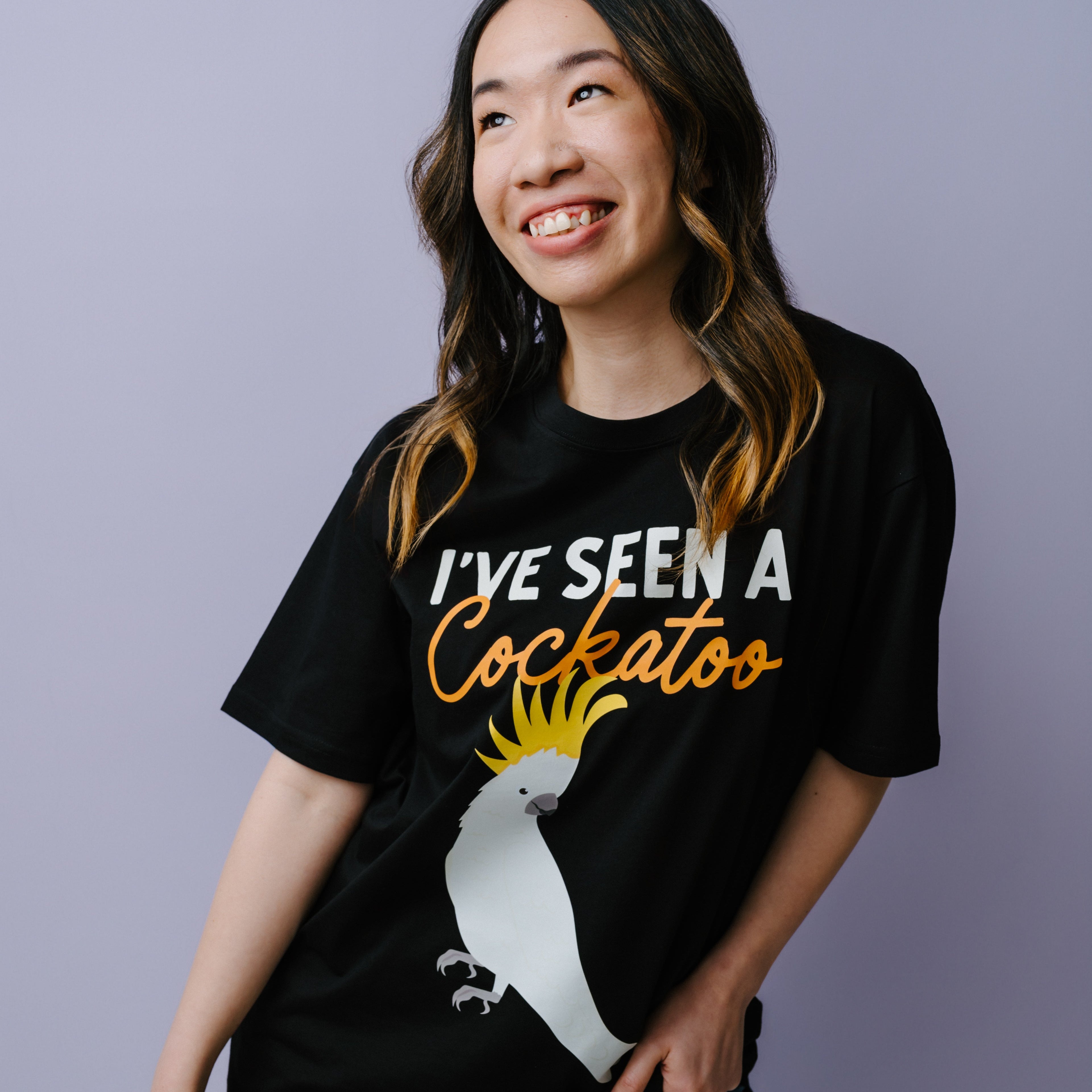 Person wearing a black t-shirt with a graphic and text, standing against a plain background. WWF-Australia cockatoo t-shirt.