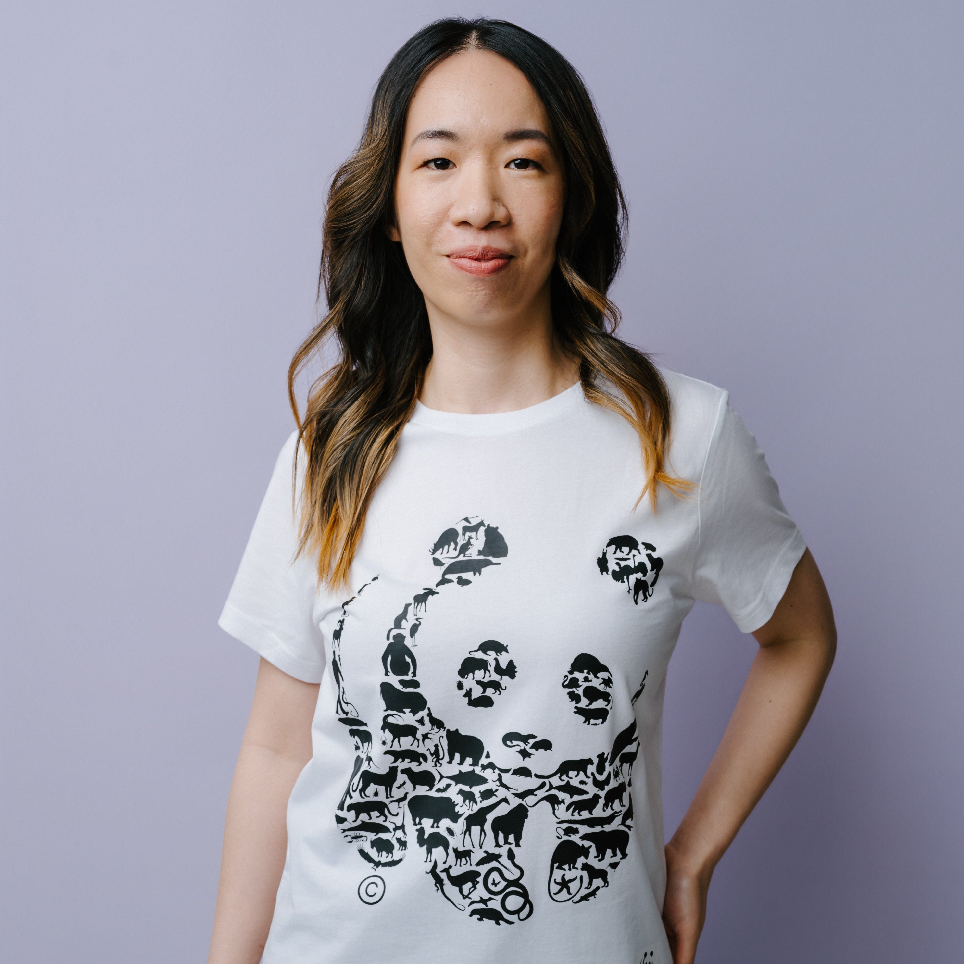 Woman wearing a white t-shirt with a black WWF panda design on a light purple background.